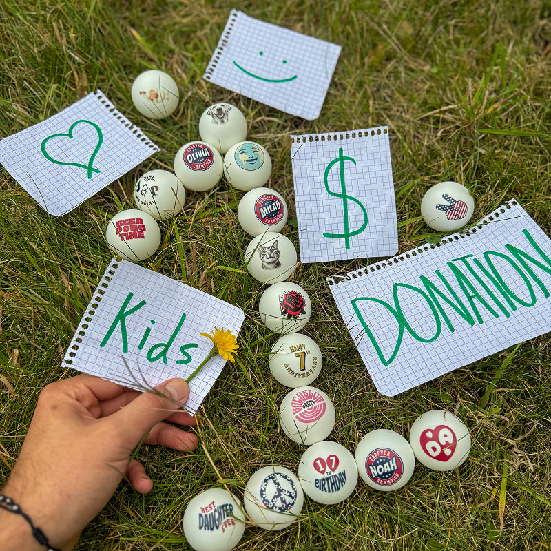 Hand holding a piece of paper with 'Kids' written on it, surrounded by personalized ping pong forming number 1 and papers with 'Donation' and heart illustration on them
