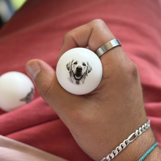 Personalized ping pong ball with a dog design held in a hand